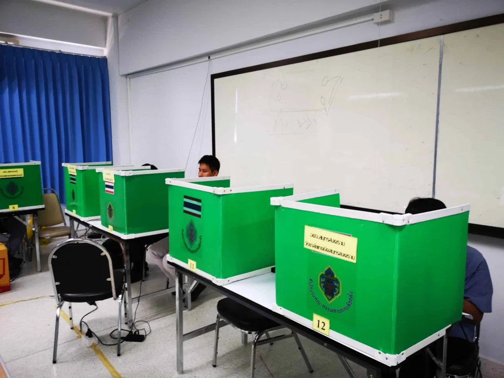 ห้องแข่งขันทักษะวิชาชีพ มีคอกกั้นสีเขียวตั้งบนโต๊ะเรียงเป็นแถว ผู้เข้าแข่งขันนั่งทำงานอยู่ในแต่ละคอก