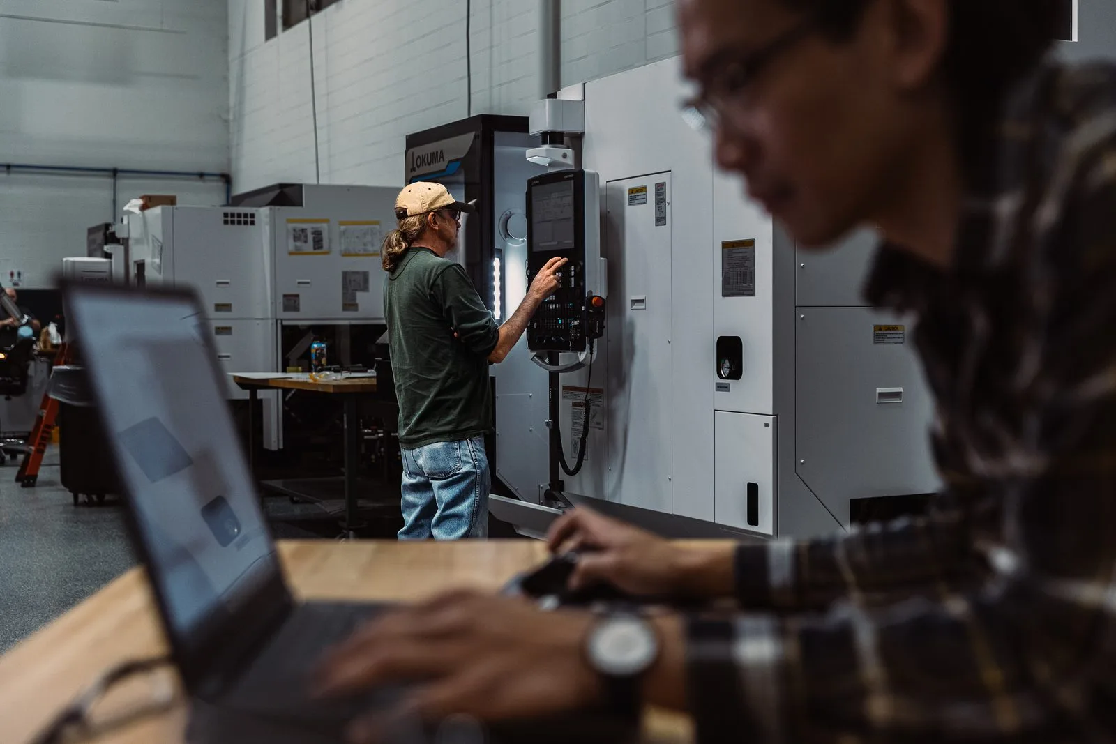 ผู้ใช้งานกำลังทำงานกับโปรแกรม CAD/CAM ที่โต๊ะทำงานในโรงงาน